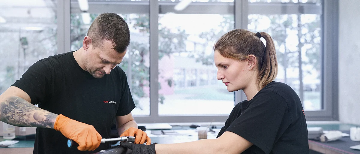Zwei Techniker der DRF Aviation Services arbeiten an einer Kufe eines Hubschraubers.